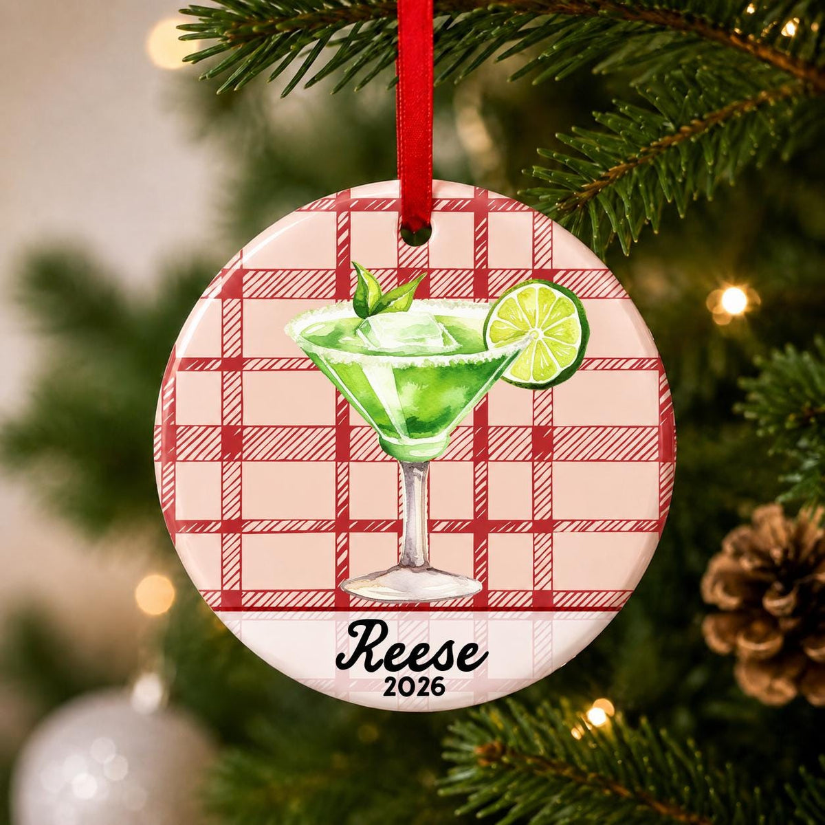 Close-up of the personalized margarita ceramic ornament with name and year on red plaid hanging on a Christmas tree