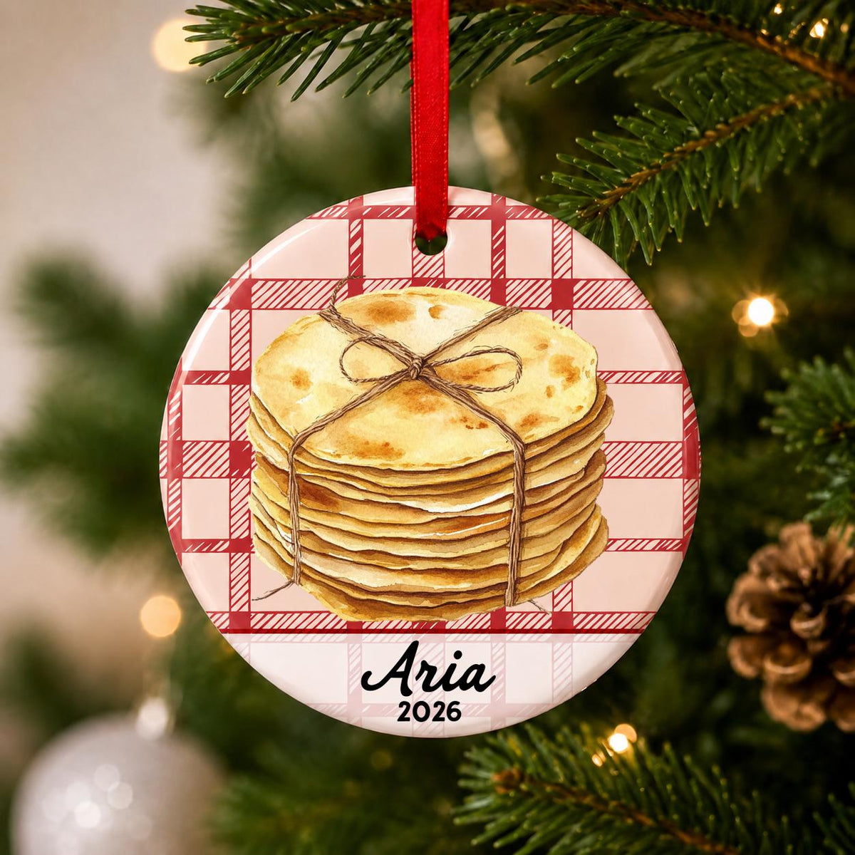 Close-up of the personalized tortilla ceramic ornament with name and year on red plaid hanging on a Christmas tree