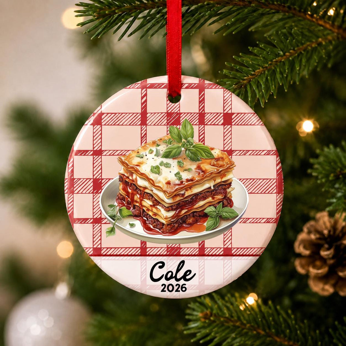 Close-up of the personalized lasagna ceramic ornament with name and year on red plaid hanging on a Christmas tree