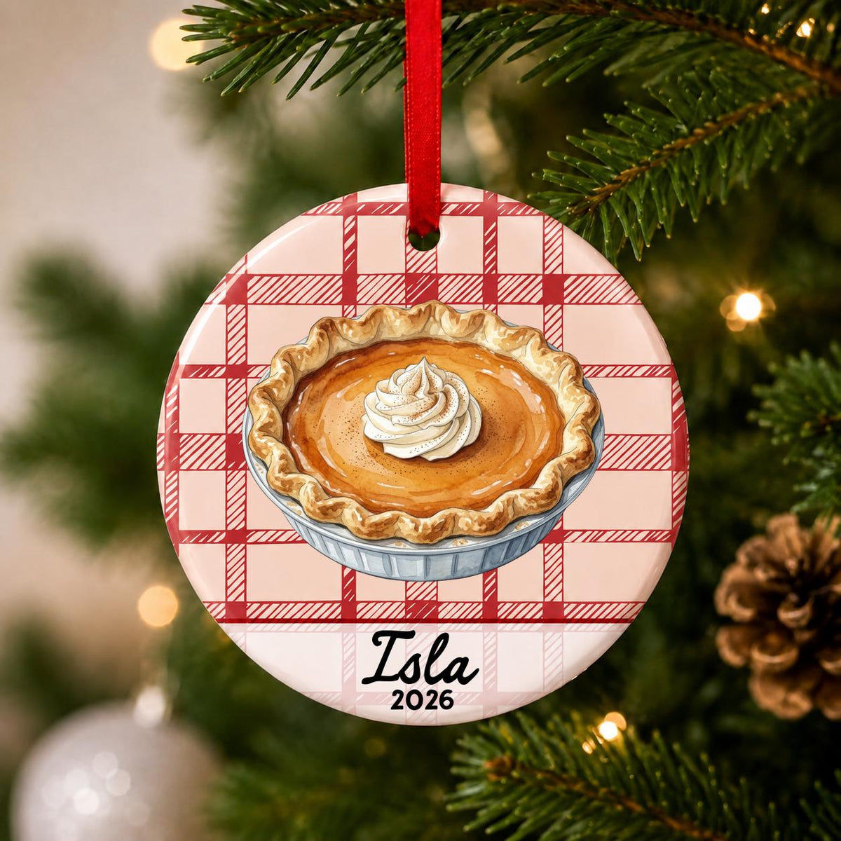 Close-up of the personalized pumpkin pie ceramic ornament with name and year on red plaid hanging on a Christmas tree