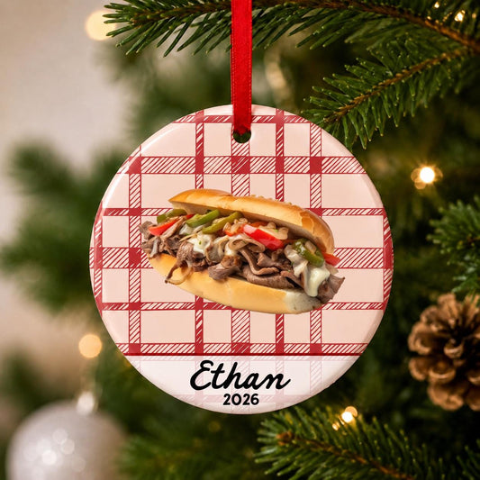 Close-up of the personalized Philly cheesesteak ceramic ornament with name and year on red plaid hanging on a Christmas tree