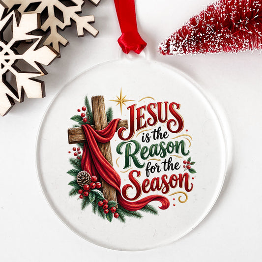 Jesus Is The Reason For The Season Cross UV DTF sticker applied to a clear round acrylic ornament with a red ribbon