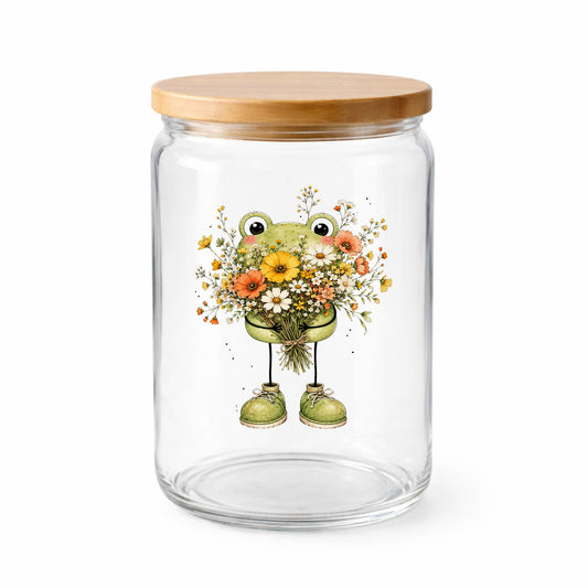 Green Frog Holding Wildflower Bouquet UV DTF sticker applied to a clear glass jar with a wooden lid