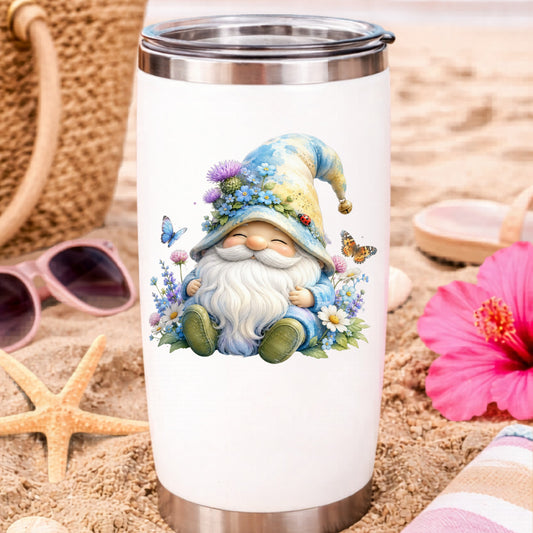 Wildflower Gnome With Butterflies UV DTF sticker applied to a white travel tumbler on beach sand