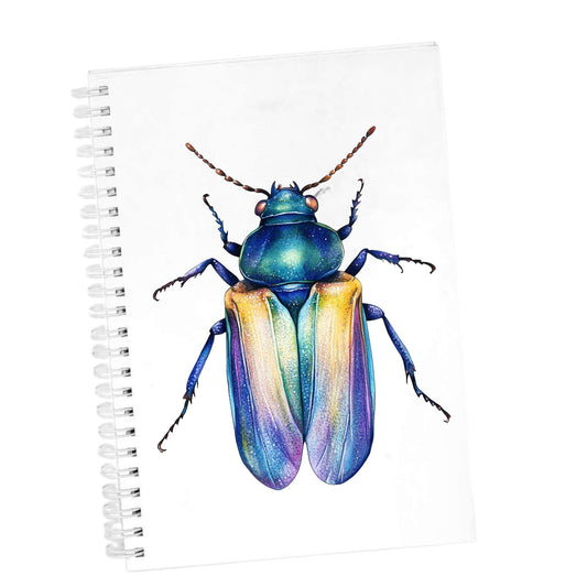 Gold And Blue Jewel Beetle UV DTF sticker applied to the cover of a white spiral journal