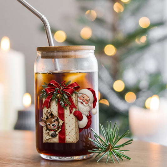 Santa Behind Polka Dot Gift With Reindeer UV DTF sticker applied to a glass can cup of iced coffee with a straw