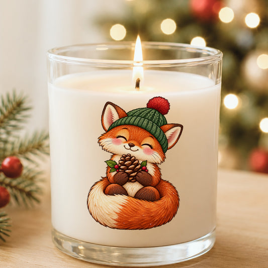 Red Fox In Knit Beanie Holding Pinecone UV DTF sticker applied to a white candle in a glass holder near Christmas lights