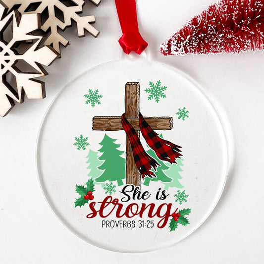 She Is Strong Christmas Cross UV DTF sticker applied to a clear round acrylic ornament with a red ribbon