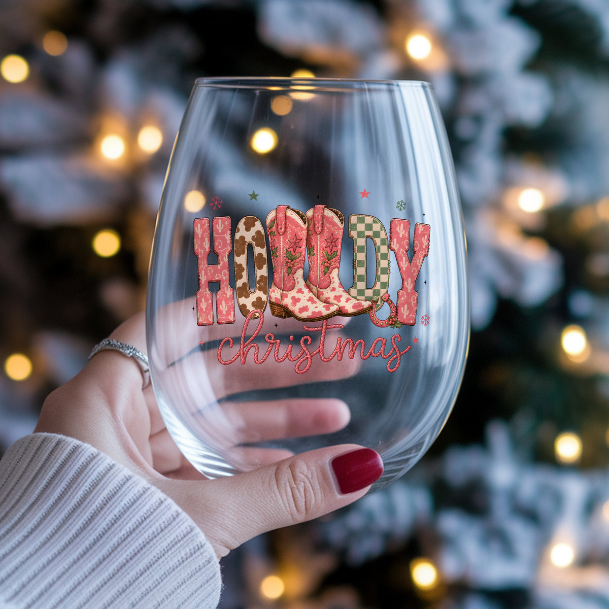Howdy Christmas Cowboy Boots UV DTF sticker applied to a stemless wine glass held in hand
