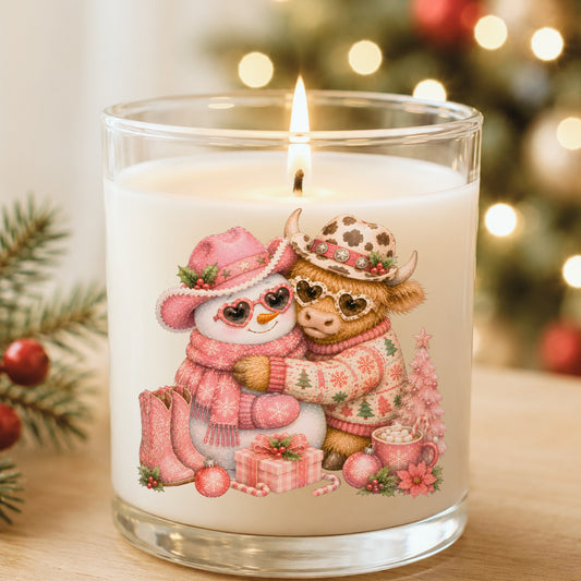 Snowman Highland Cow Christmas Hug UV DTF sticker applied to a white candle in a glass holder near Christmas lights