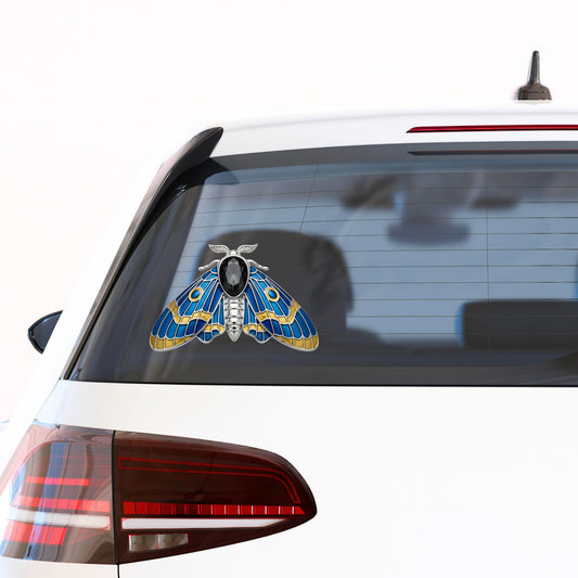 Silver Blue Enamel Moth UV DTF sticker applied to the rear window of a white car