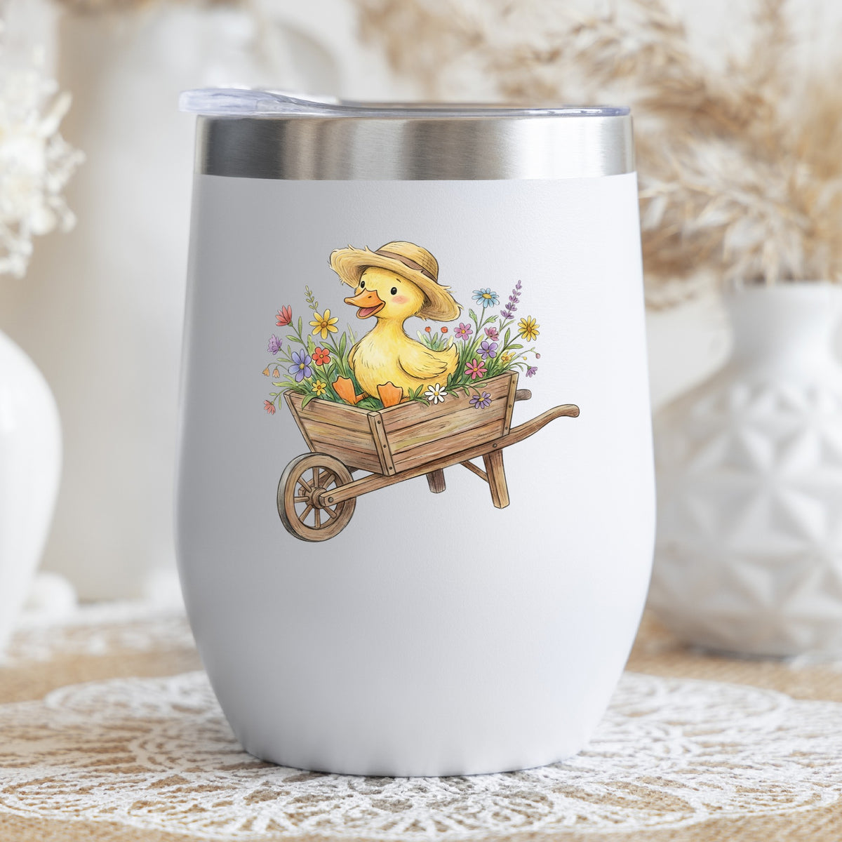 Duckling In Wheelbarrow Of Flowers UV DTF sticker applied to a white stemless tumbler with a lid