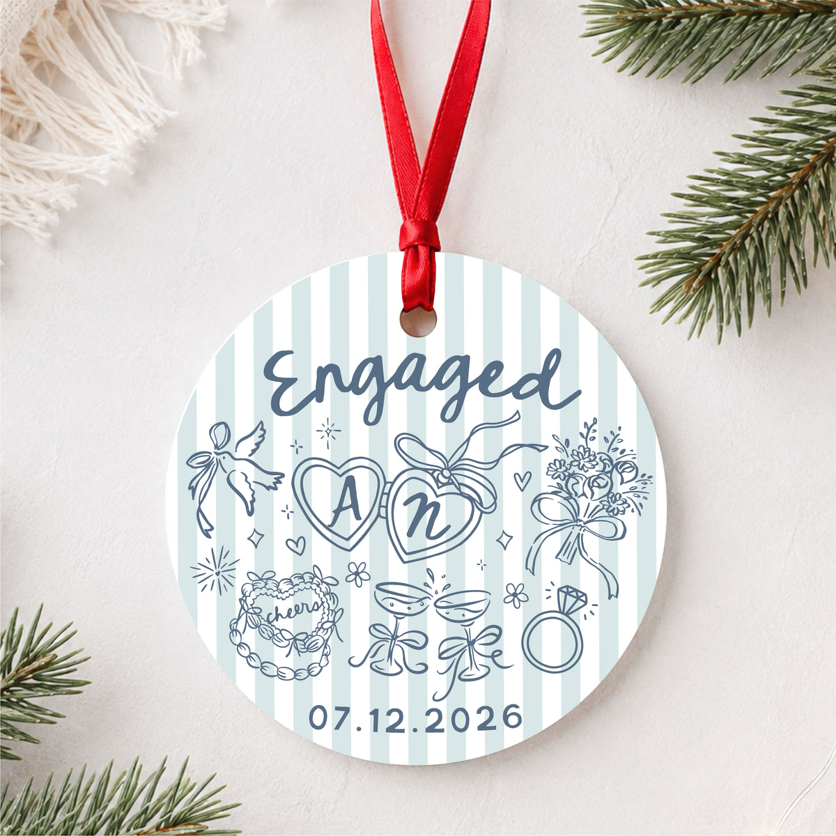 Personalized blue striped engagement ornament with initials and full date, styled flat lay hero view