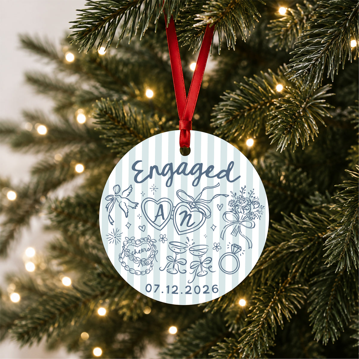 Personalized blue striped engagement ornament with initials and full date, hanging on a lit Christmas tree