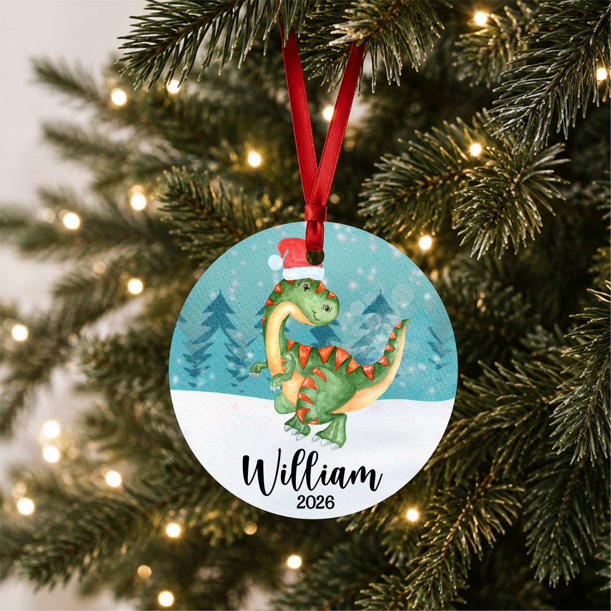 Personalized watercolor Christmas dinosaur ornament with child's name and year, hanging on a lit Christmas tree