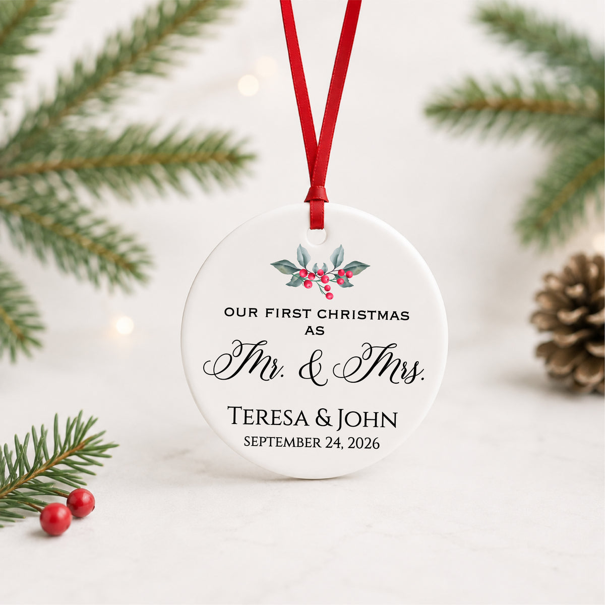 Personalized first Christmas as Mr. and Mrs. ornament with holly, couple names and wedding date, hanging in a bright evergreen setting