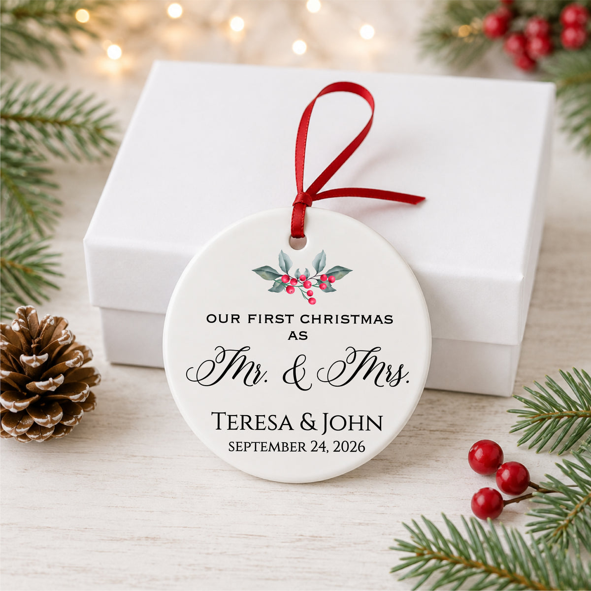 Personalized first Christmas as Mr. and Mrs. ornament with holly, couple names and wedding date, displayed beside a white gift box