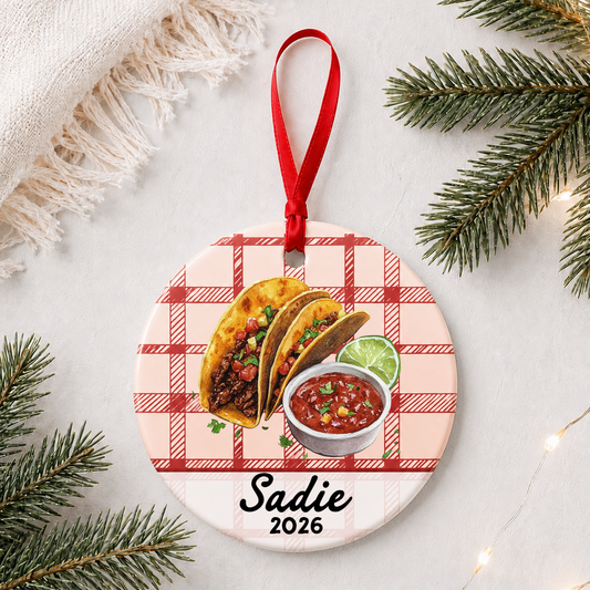 Personalized taco ceramic ornament with name and year on red plaid styled with pine branches on a soft white background