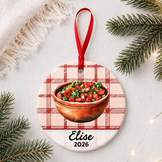 Personalized pico de gallo ceramic ornament with name and year on red plaid styled with pine branches on a soft white background