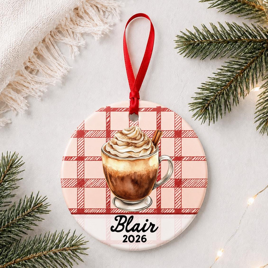 Personalized Mexican hot chocolate ceramic ornament with name and year on red plaid styled with pine branches on a soft white background
