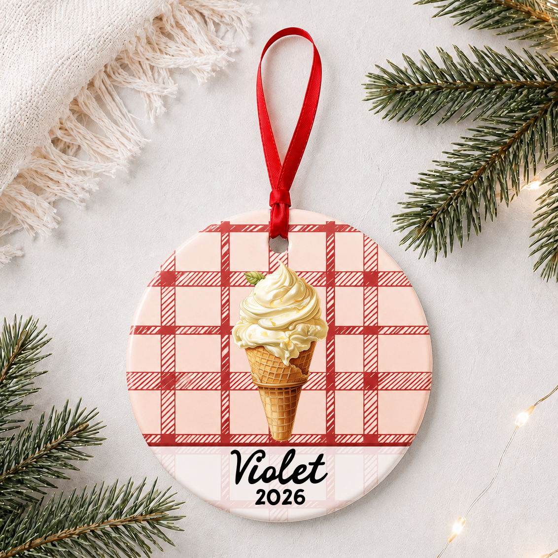 Personalized soft serve ice cream ceramic ornament with name and year on red plaid styled with pine branches on a soft white background