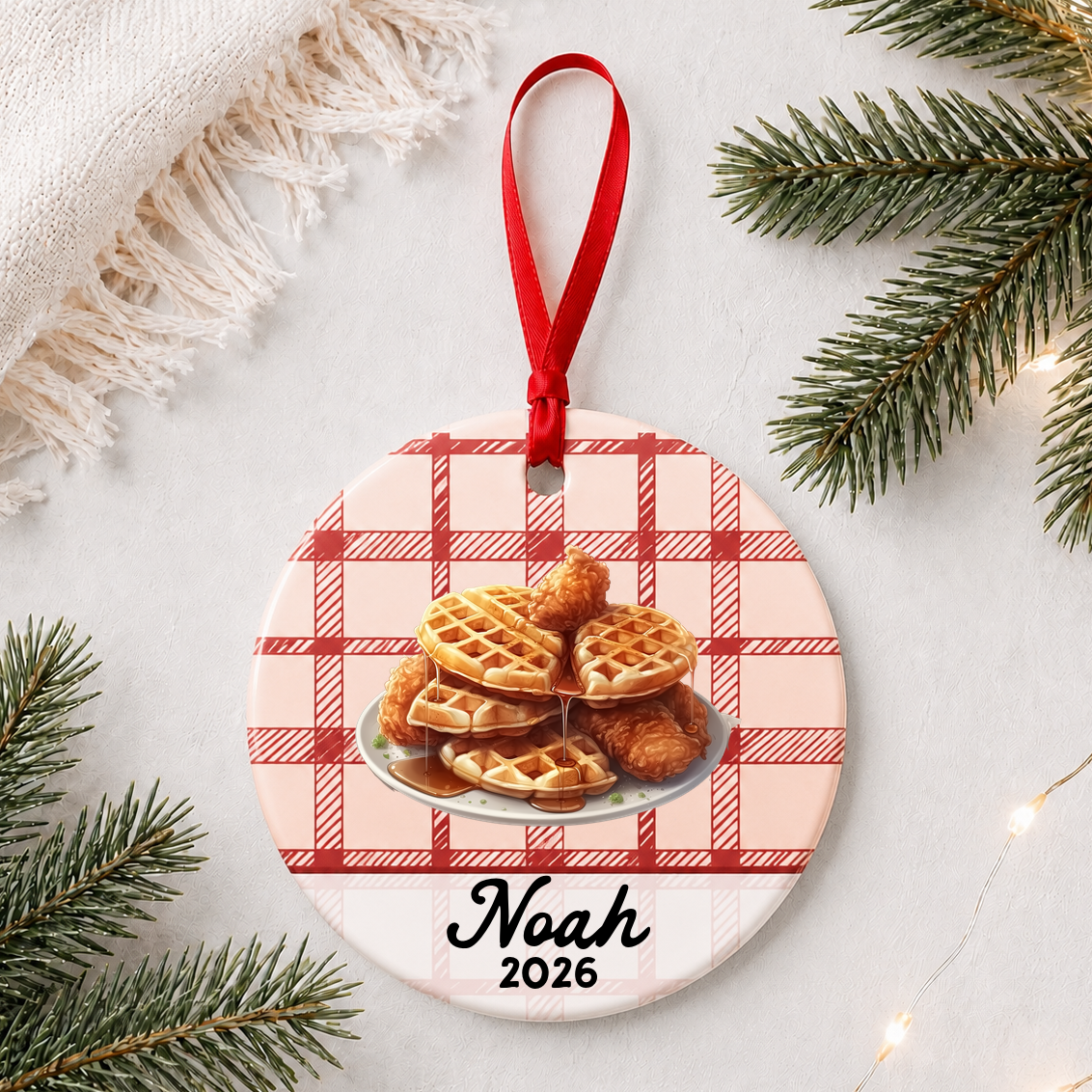 Personalized chicken and waffles ceramic ornament with name and year on red plaid styled with pine branches on a soft white background