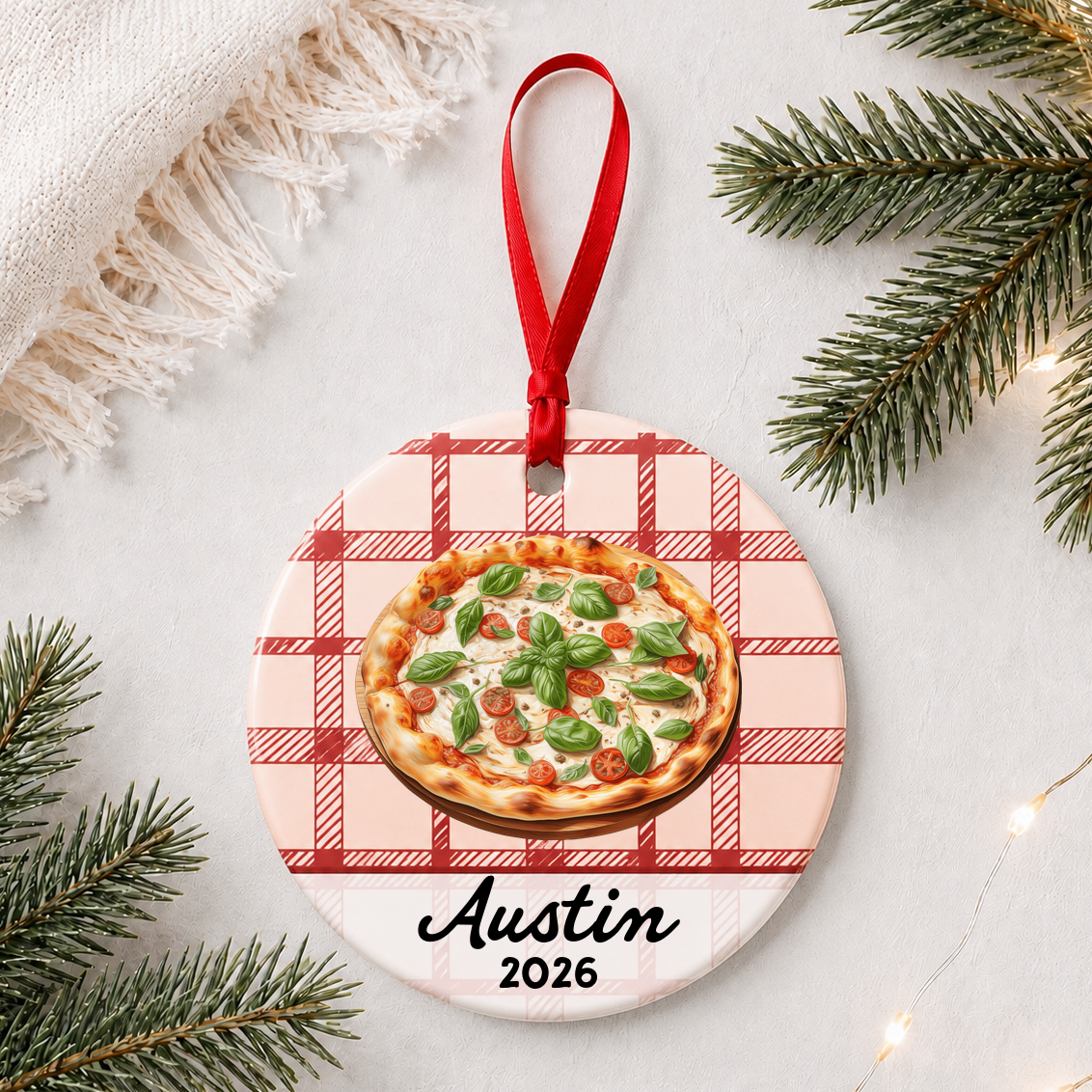 Personalized Margherita pizza ceramic ornament with name and year on red plaid styled with pine branches on a soft white background