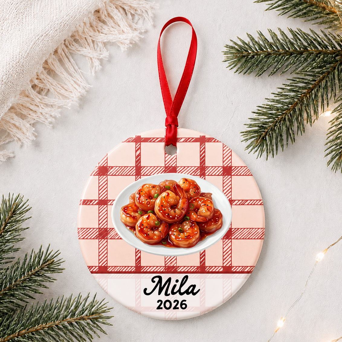 Personalized sesame shrimp ceramic ornament with name and year on red plaid styled with pine branches on a soft white background