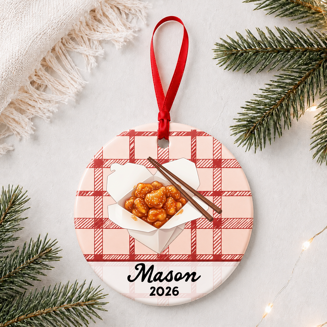 Personalized sesame chicken ceramic ornament with name and year on red plaid styled with pine branches on a soft white background