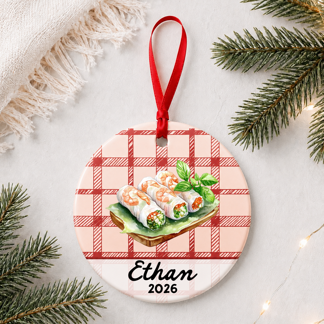 Personalized fresh spring rolls ceramic ornament with name and year on red plaid styled with pine branches on a soft white background