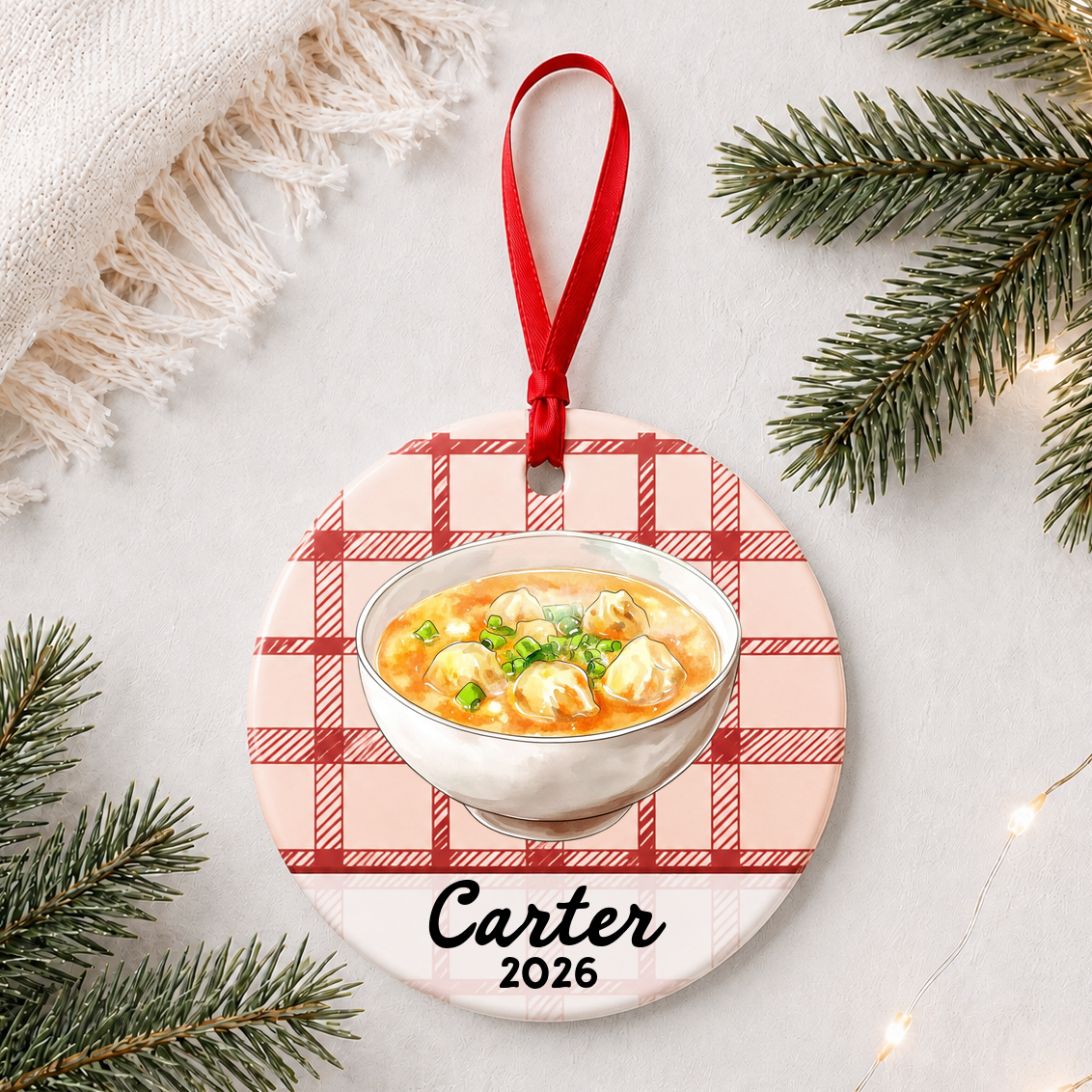 Personalized wonton soup ceramic ornament with name and year on red plaid styled with pine branches on a soft white background