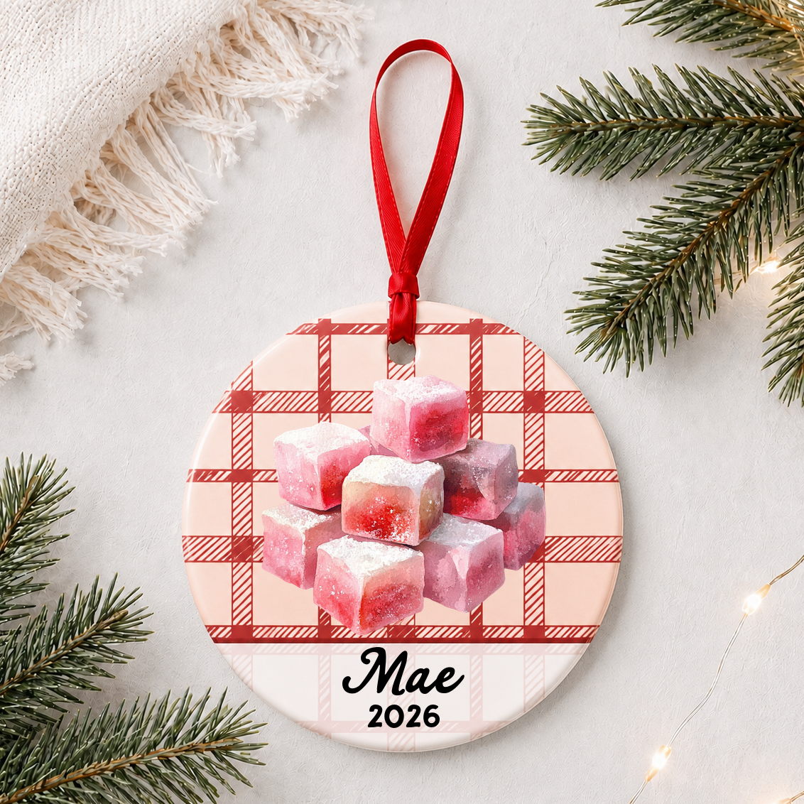 Personalized turkish delight ceramic ornament with name and year on red plaid styled with pine branches on a soft white background