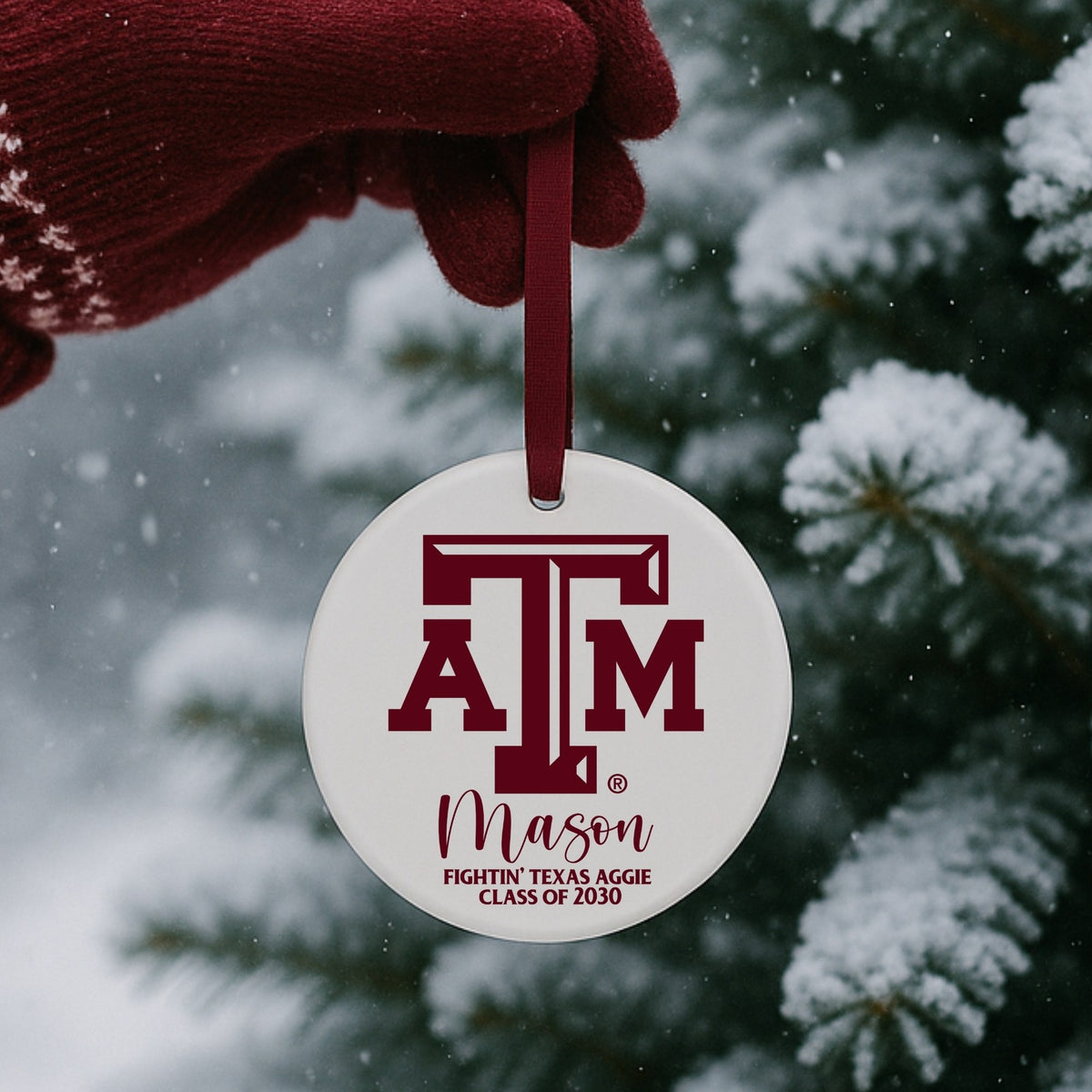 Texas A&M Aggie ceramic ornament in snowy holiday setting with maroon ribbon