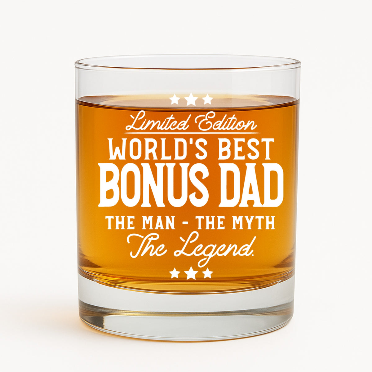 Lifestyle photo of engraved Bonus Dad whiskey glass on wood table with ice and bokeh lights – great stepdad gift.