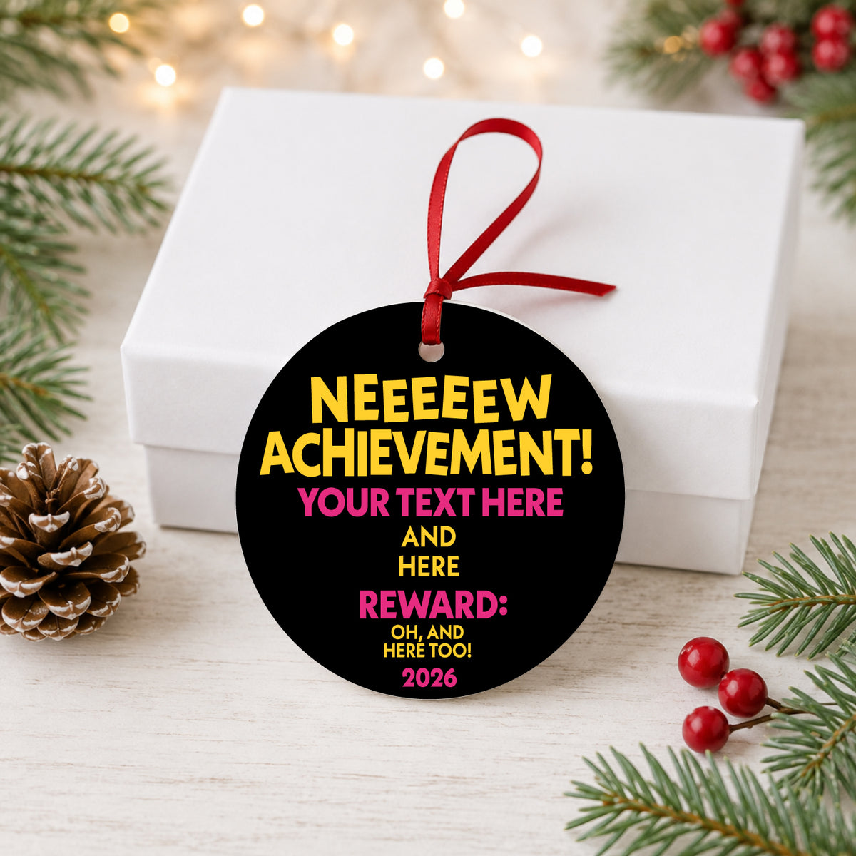 Custom achievement ornament with red ribbon beside a white gift box