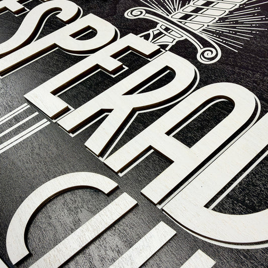 Close-up of raised white lettering and decorative details on the black layered wood Dungeon Crawler Carl Desperado Club sign
