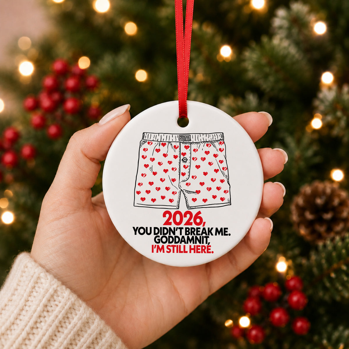Dungeon Crawler Carl heart boxers 2026 ornament held in hand in front of a lit Christmas tree