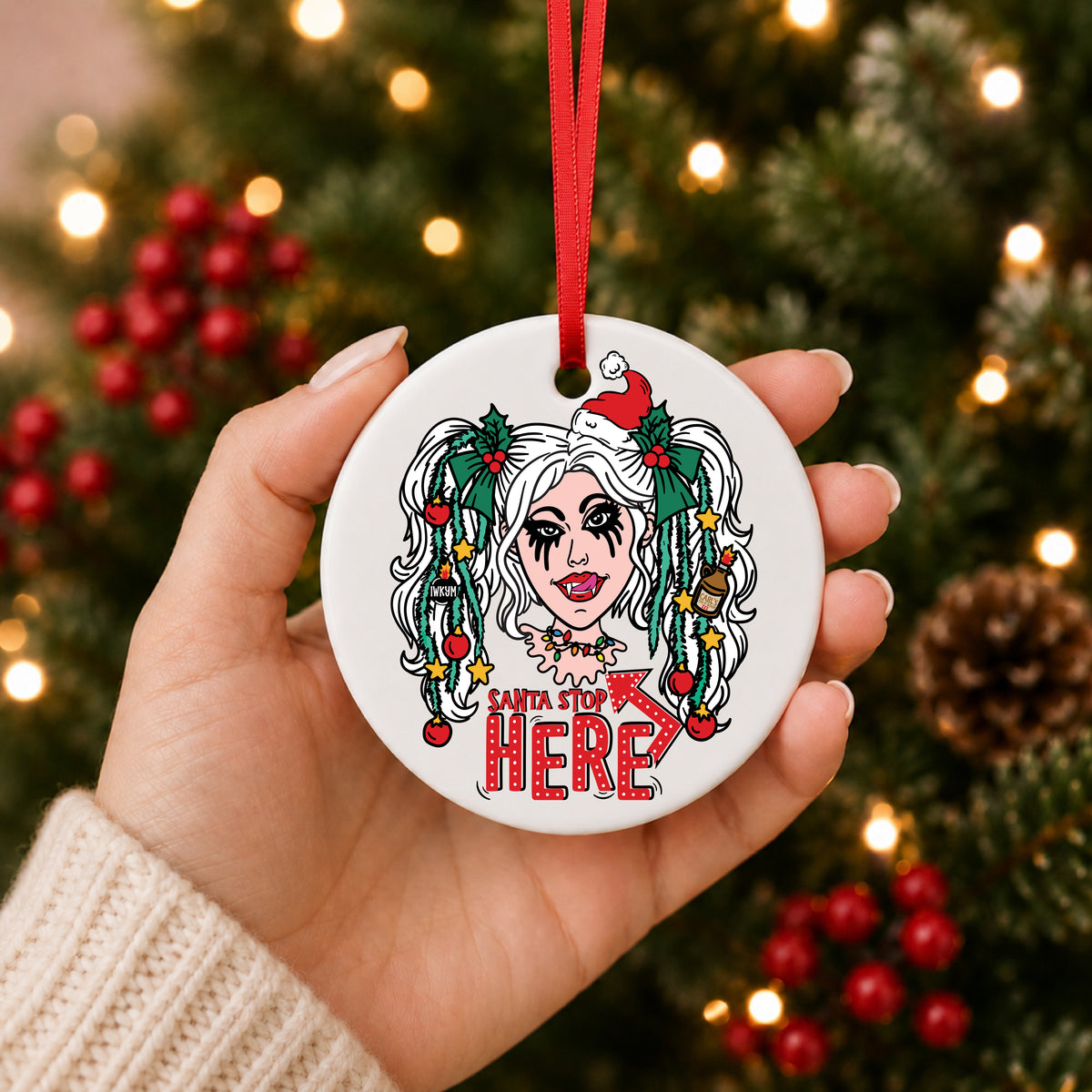 Dungeon Crawler Carl Samantha Santa Stop Here ornament held in hand in front of a lit Christmas tree