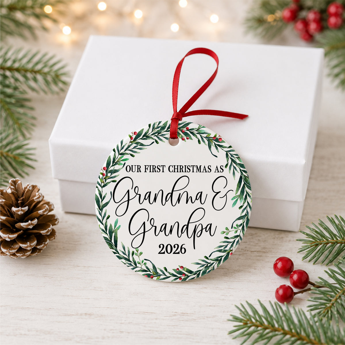 Grandma and Grandpa first Christmas ornament displayed with a white gift box and holiday greenery