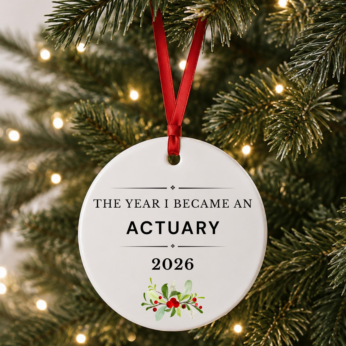 Actuary 2026 ceramic ornament reading The Year I Became an Actuary hanging on a lit Christmas tree