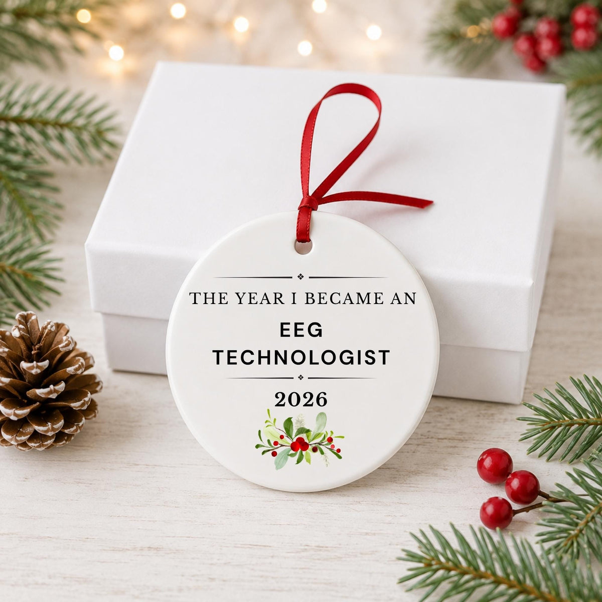 EEG Technologist 2026 ceramic ornament reading The Year I Became an EEG Technologist in front of a white gift box with pinecones and red berries