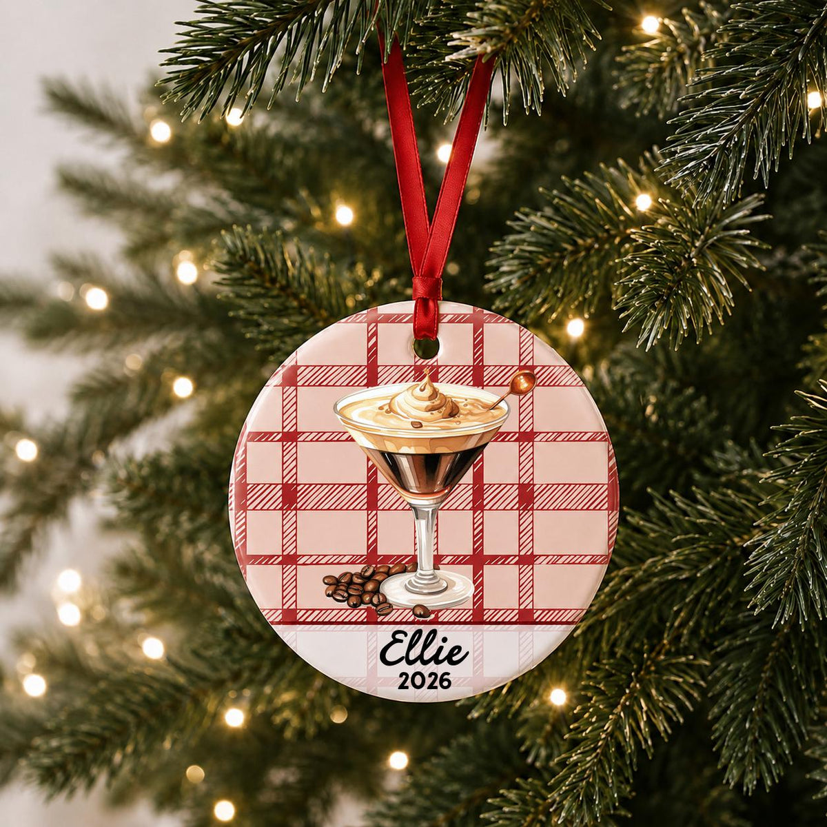 Personalized espresso martini ceramic ornament with name and year on red plaid hanging on a lit Christmas tree