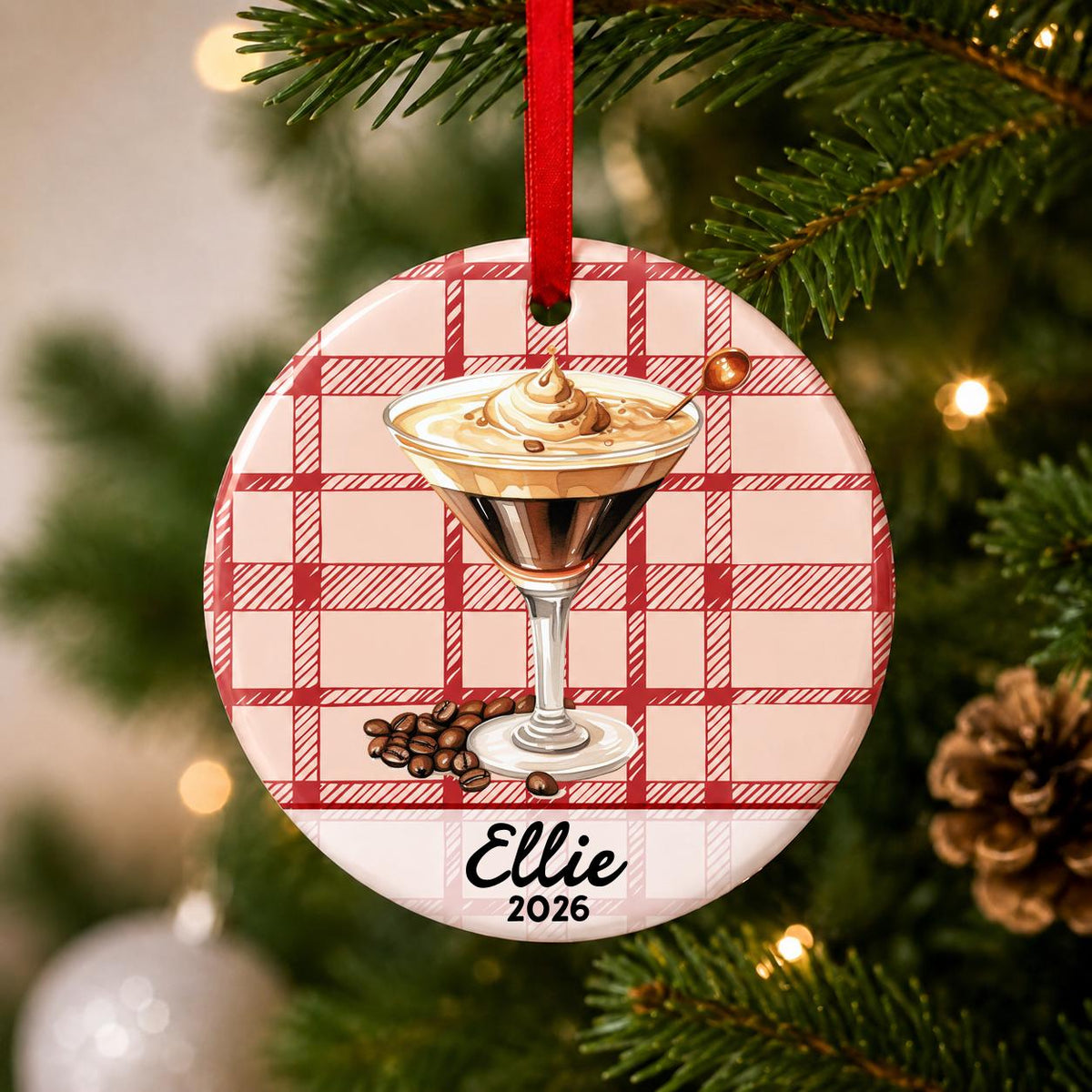 Close-up of the personalized espresso martini ceramic ornament with name and year on red plaid hanging on a Christmas tree