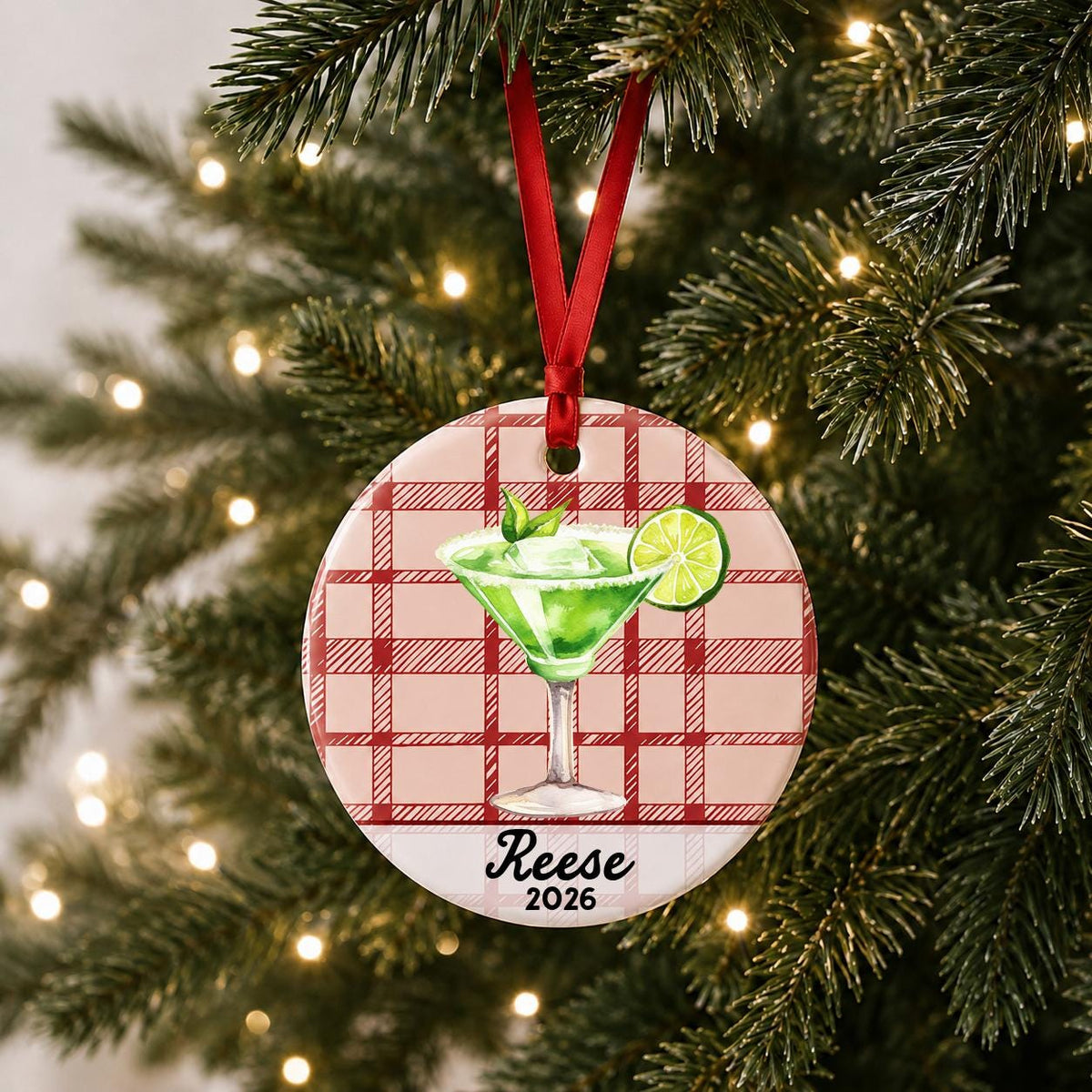Personalized margarita ceramic ornament with name and year on red plaid hanging on a lit Christmas tree