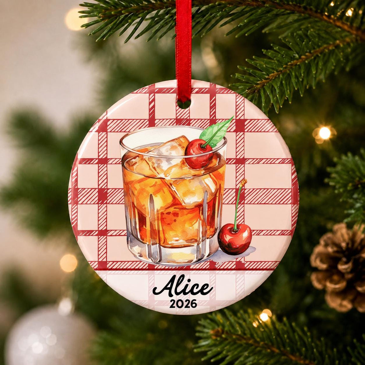 Close-up of the personalized Old Fashioned cocktail ceramic ornament with name and year on red plaid hanging on a Christmas tree