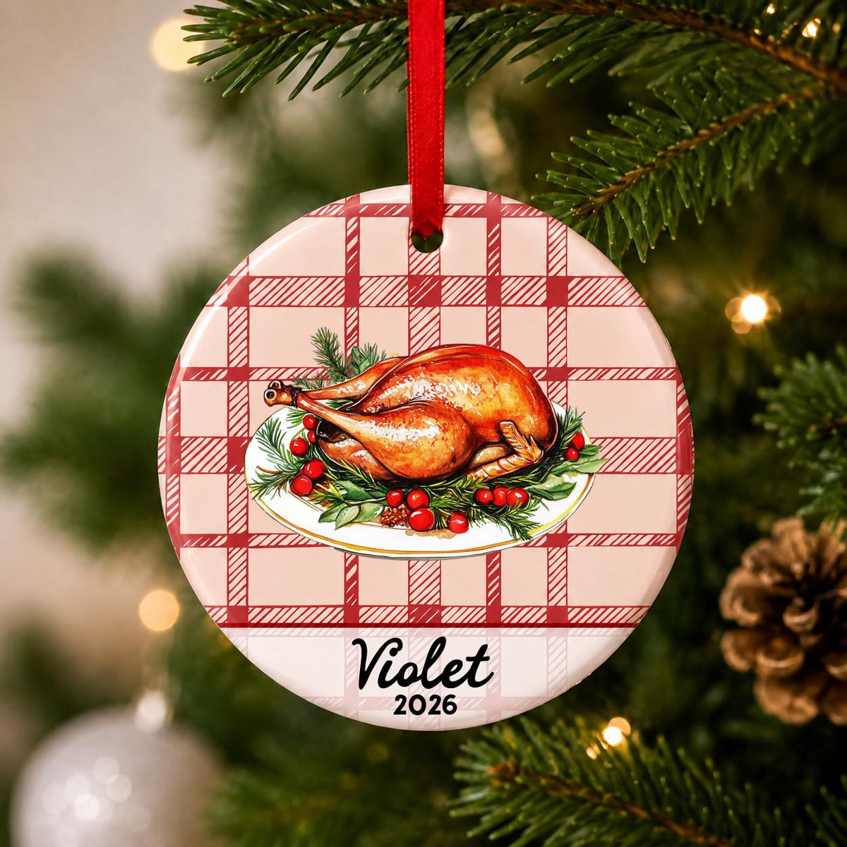 Close-up of the personalized roast turkey ceramic ornament with name and year on red plaid hanging on a Christmas tree