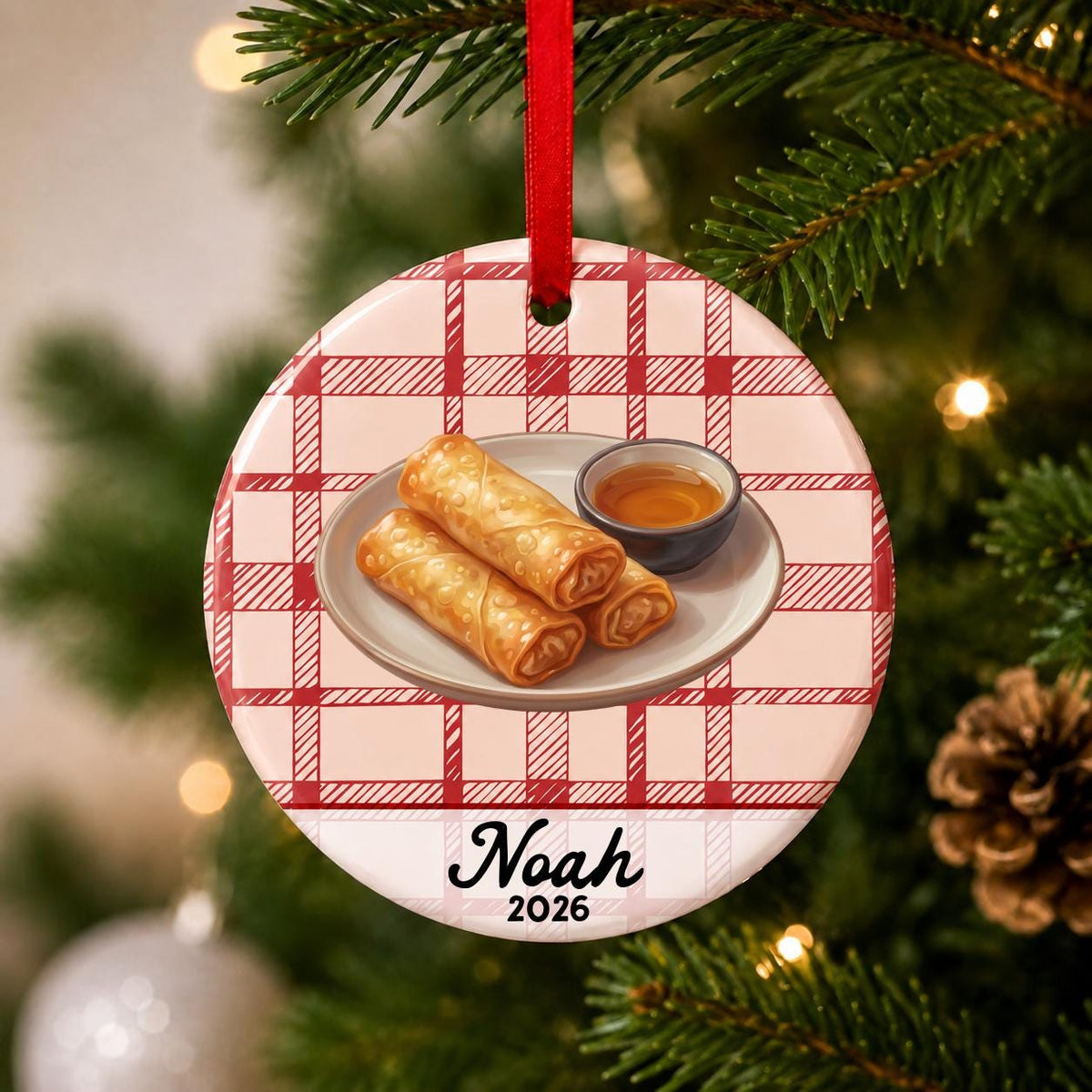 Close-up of the personalized egg roll ceramic ornament with name and year on red plaid hanging on a Christmas tree