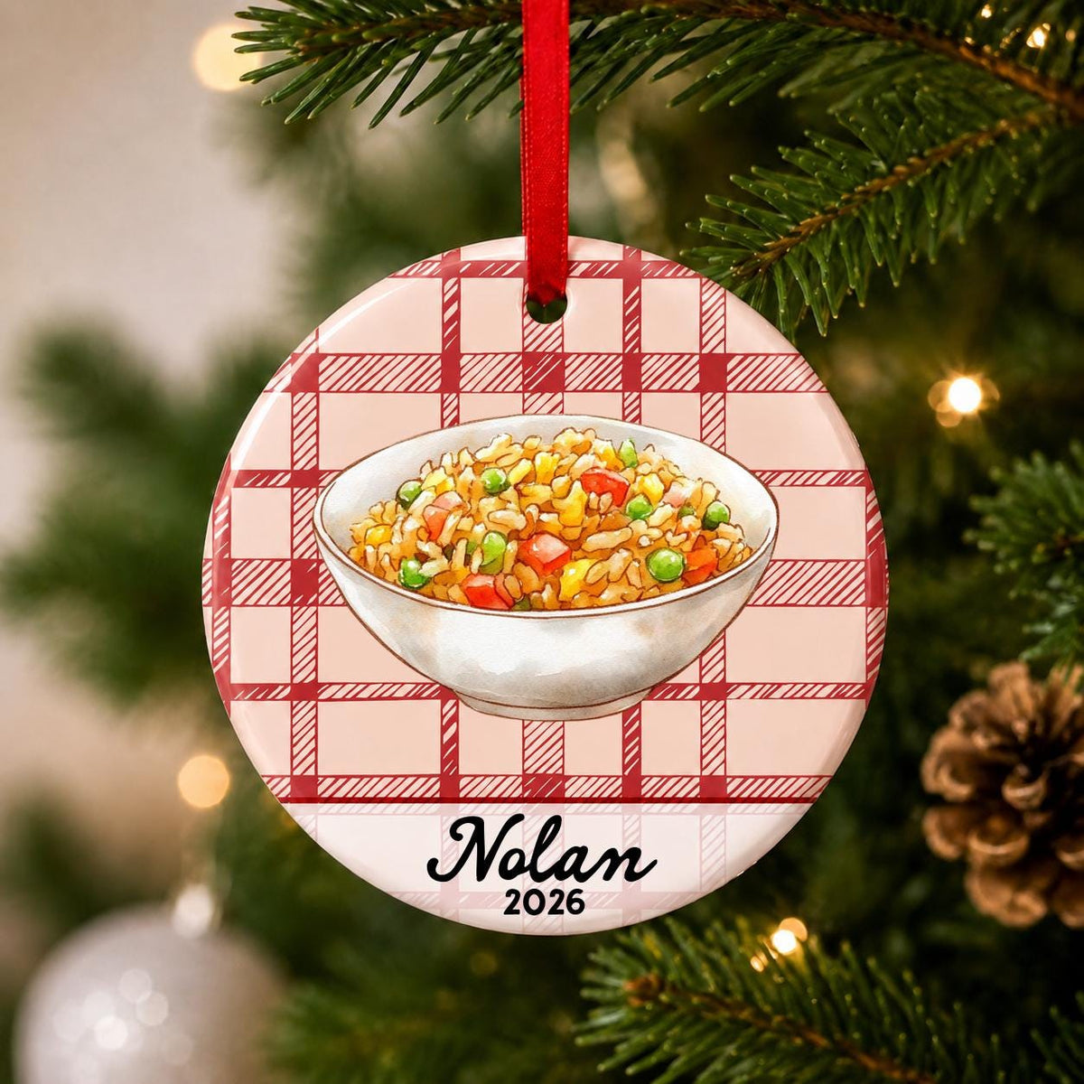 Close-up of the personalized fried rice ceramic ornament with name and year on red plaid hanging on a Christmas tree