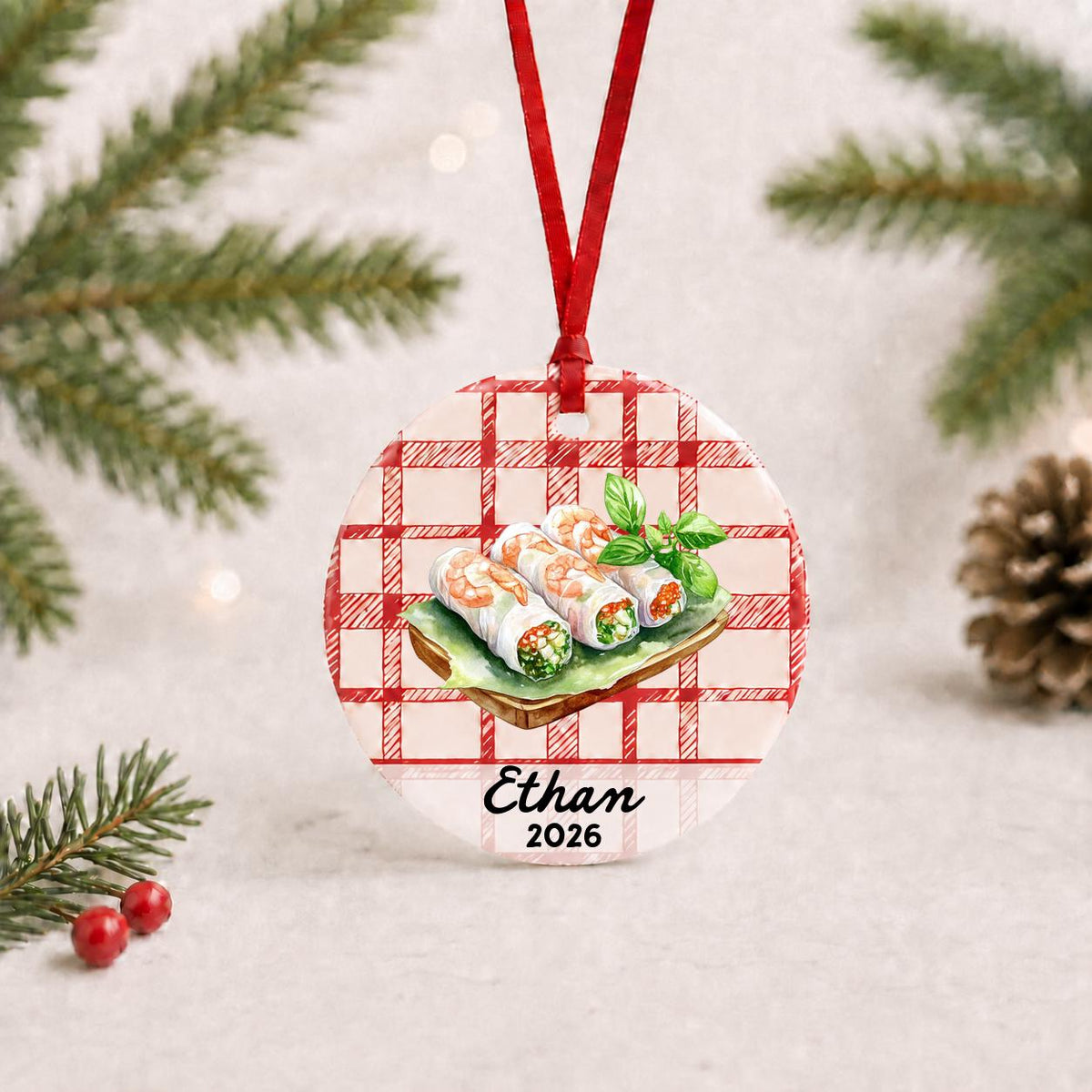 Personalized fresh spring rolls ceramic ornament with name and year on red plaid with red ribbon on a white surface with pine branches and pinecones