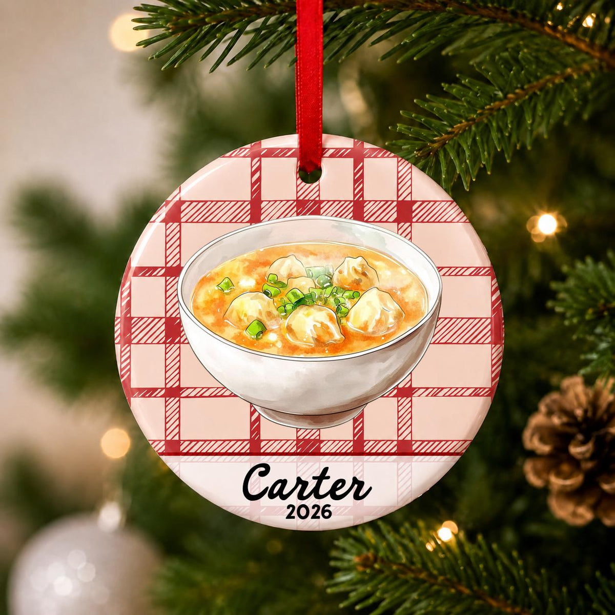 Close-up of the personalized wonton soup ceramic ornament with name and year on red plaid hanging on a Christmas tree